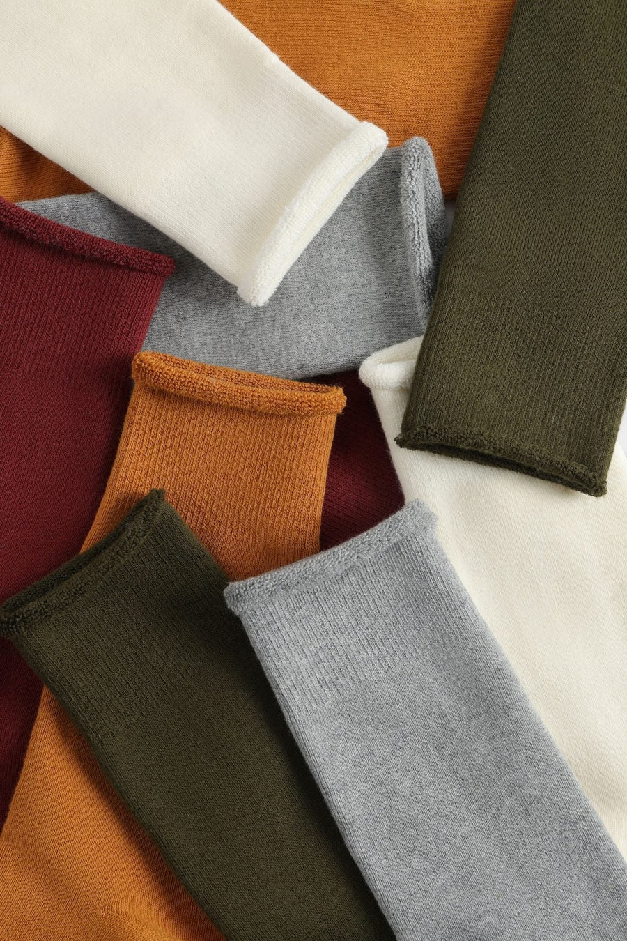 Glida rolled-cuff socks laid out in Ivory, Heather, Brick, Amber and Olive