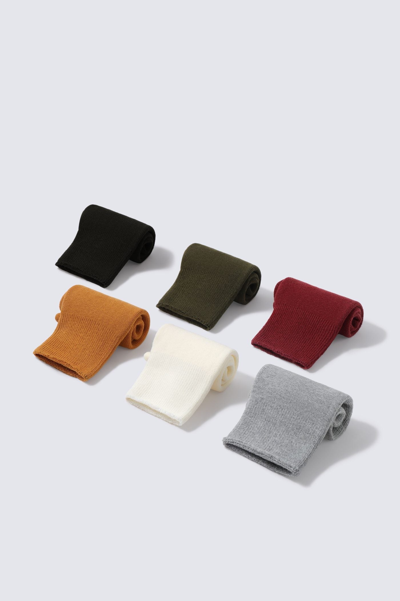 Stack of folded Glida crew socks across multiple colours