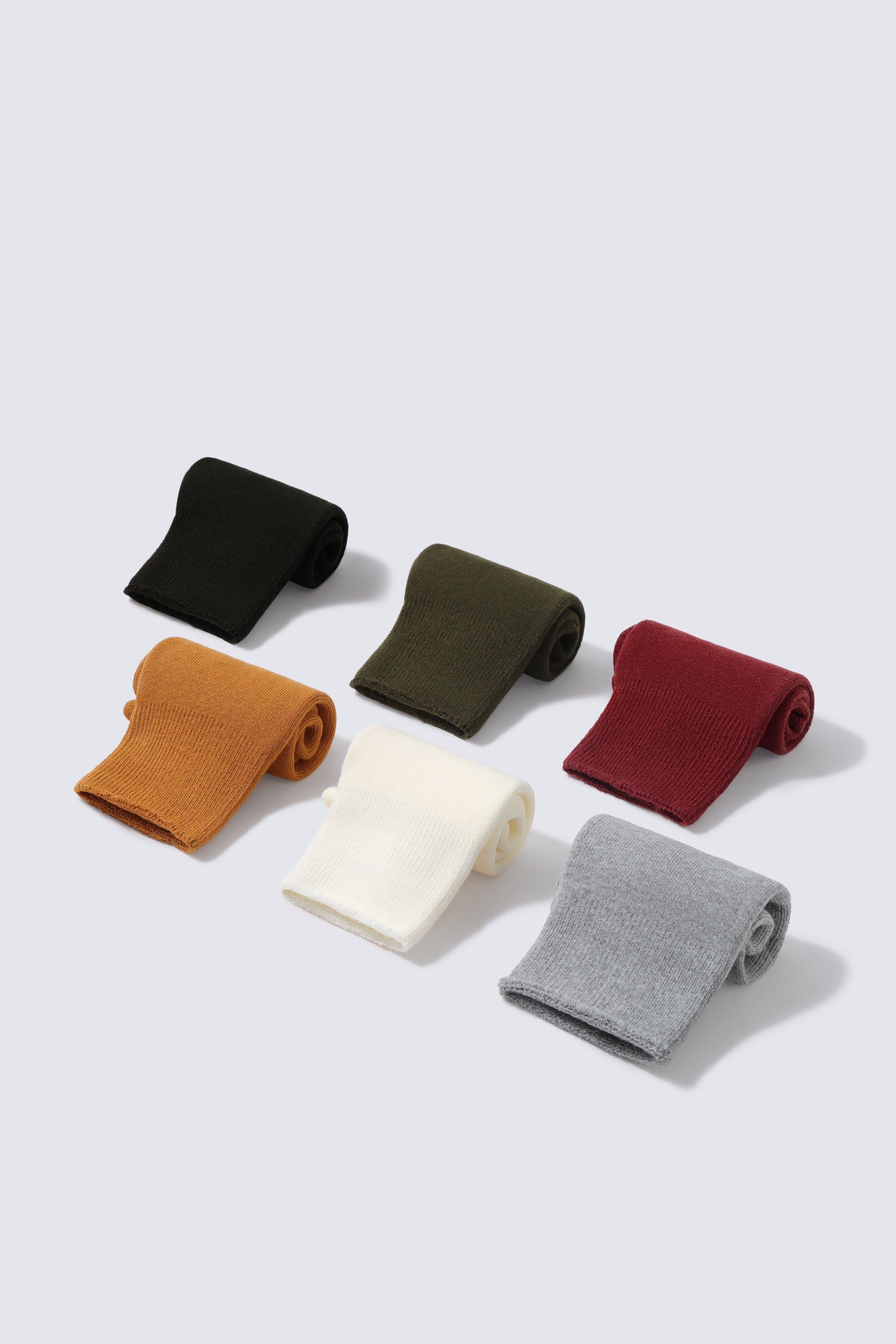 Stack of folded Glida crew socks across multiple colours
